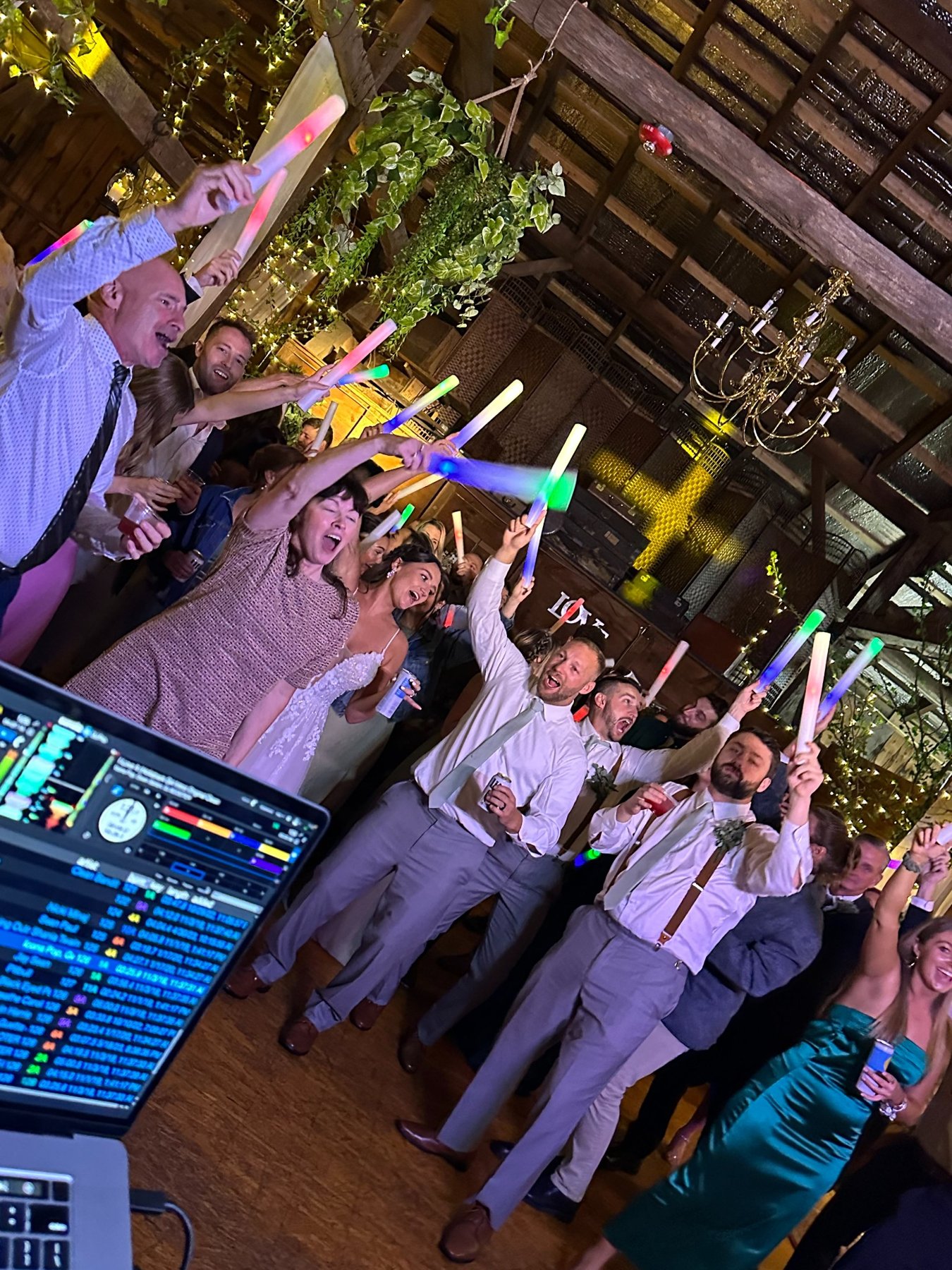 Packed wedding dance floor with glow sticks seen from DJ Puff’s booth