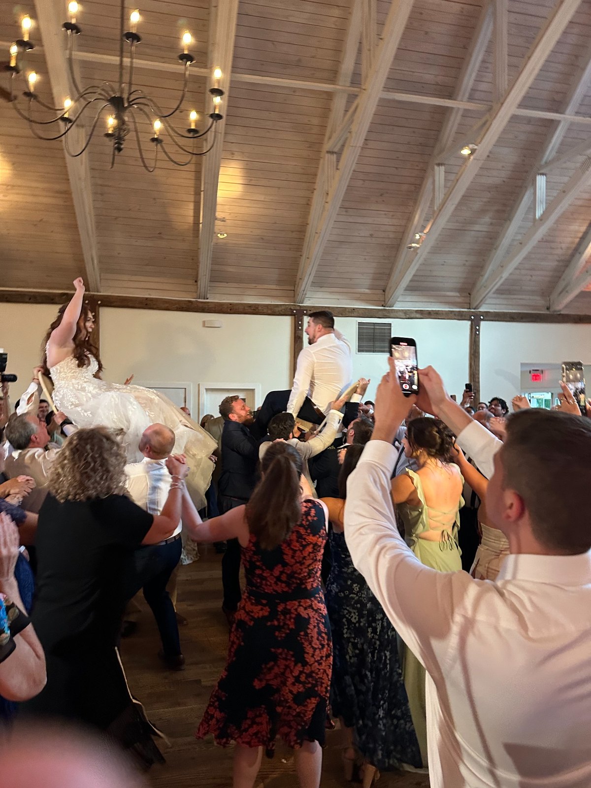 A bride and groom lifted above a packed wedding dance floor during a high-energy reception