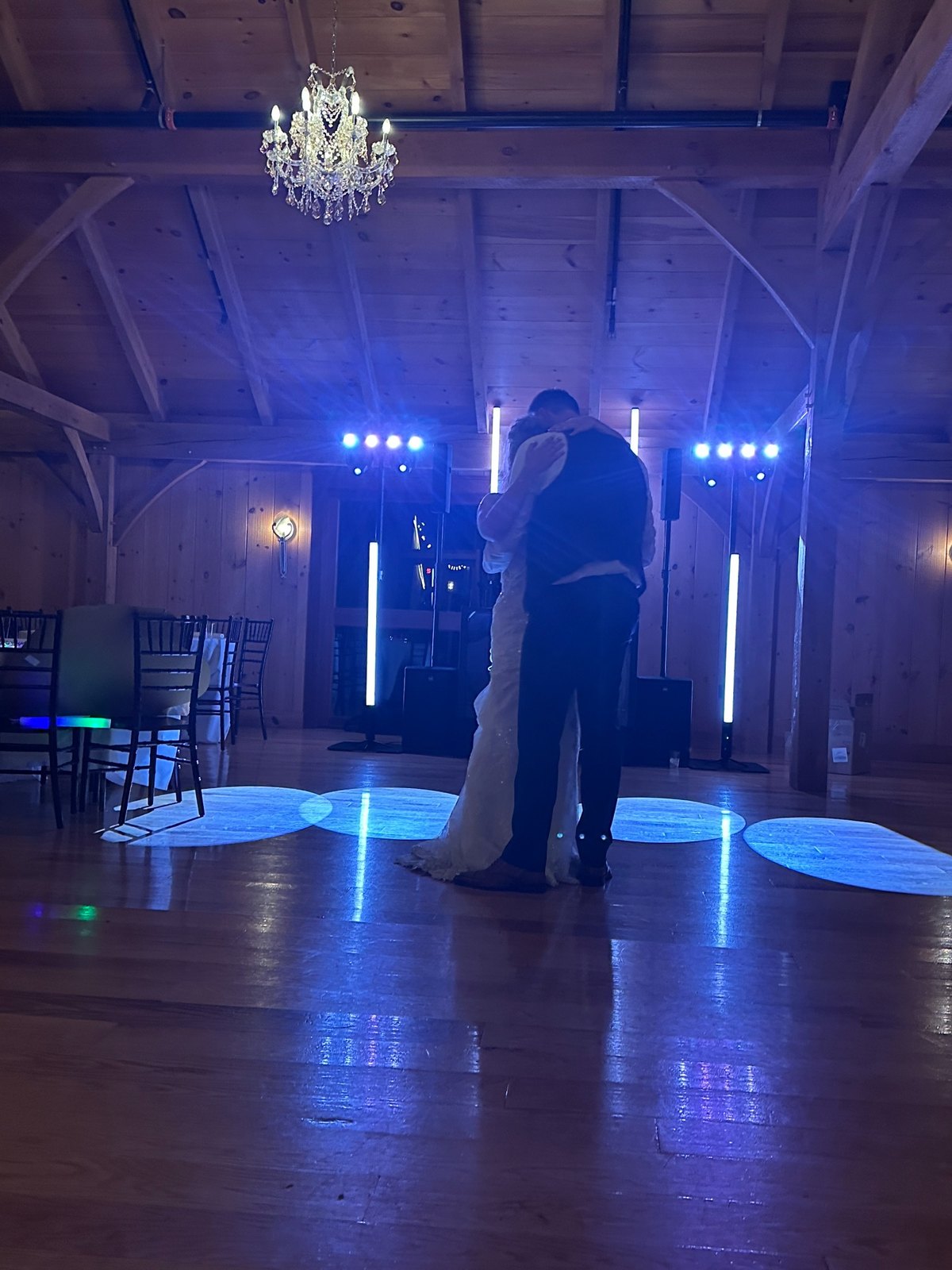 A newlywed couple sharing a first dance with DJ Puff's reception setup in the background
