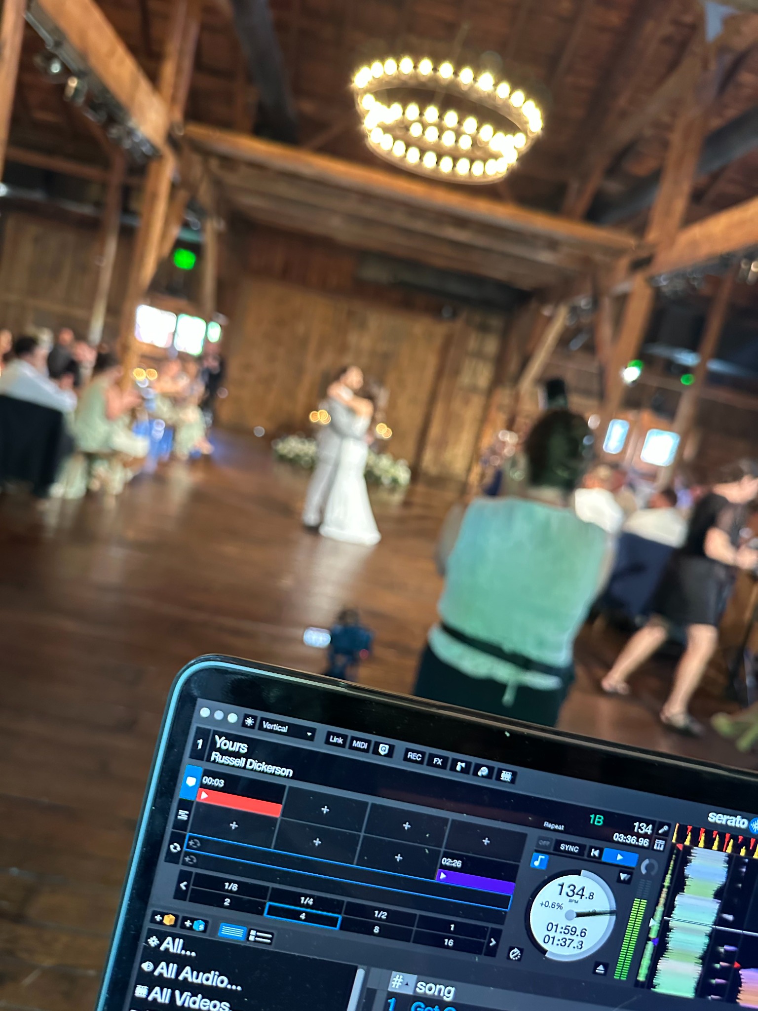 DJ Puff's view of a couple's first dance with their song visible on the DJ screen