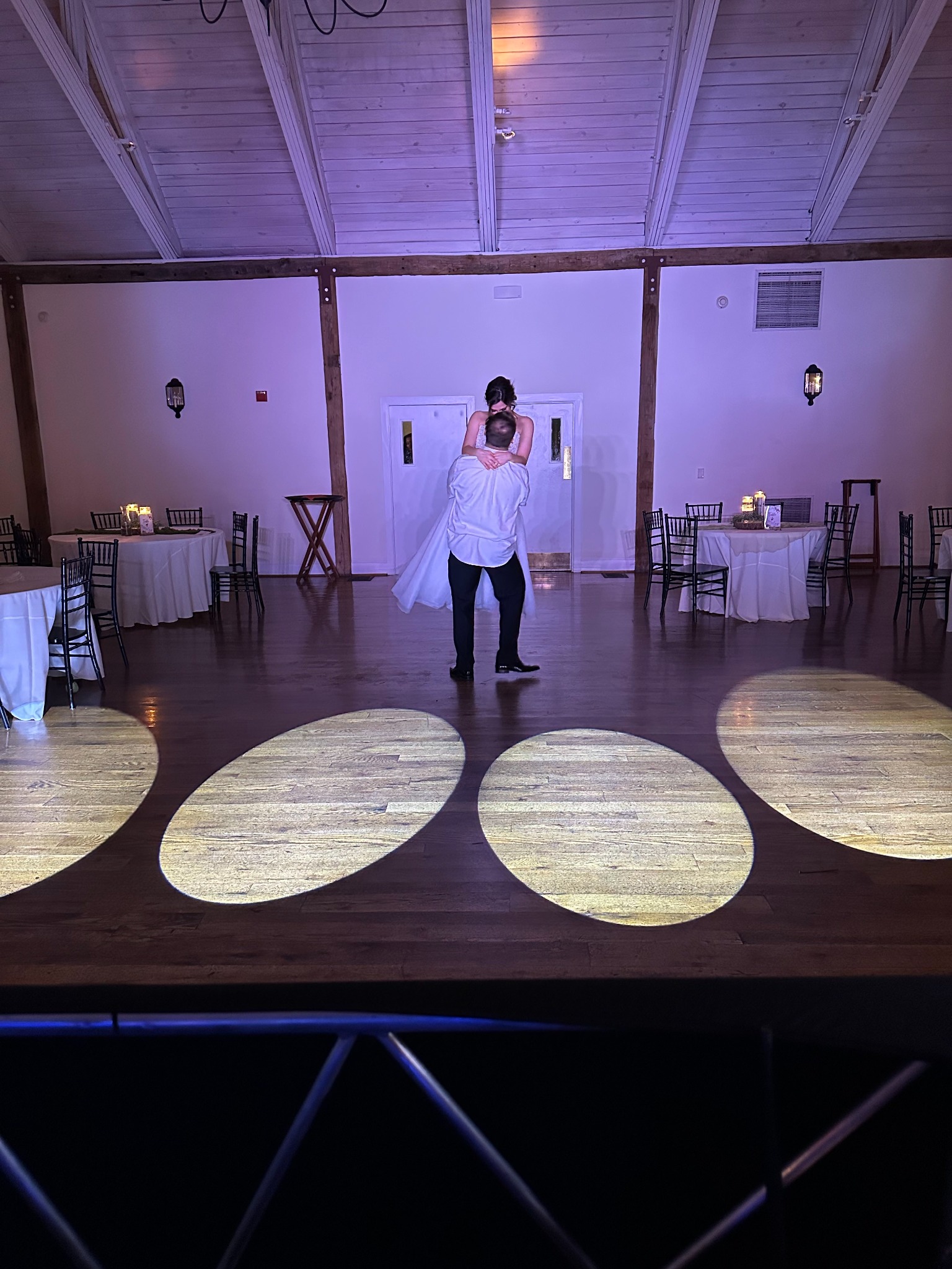 A newlywed couple dancing at their wedding reception under dramatic lighting